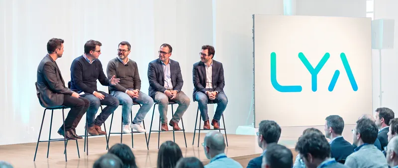 Conférence Lya : une table ronde d'intervenants sur scène, le logo Lya affiché à l'écran, face au public.